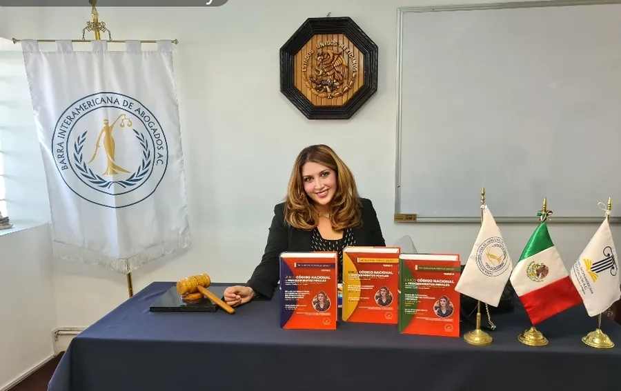 La Dra. González Obregón en una mesa con los tres tomos del Código Nacional de Procedimientos Penales comentado